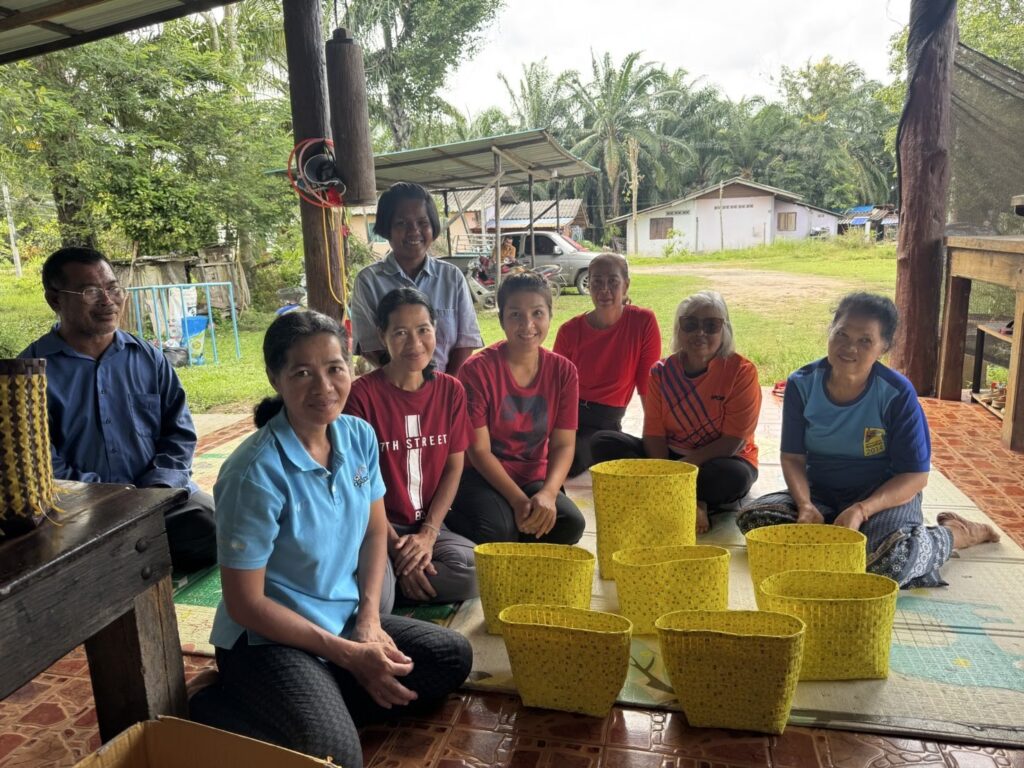 Informal workers from a community in southern Thailand sit with the baskets they weaved for Morph.