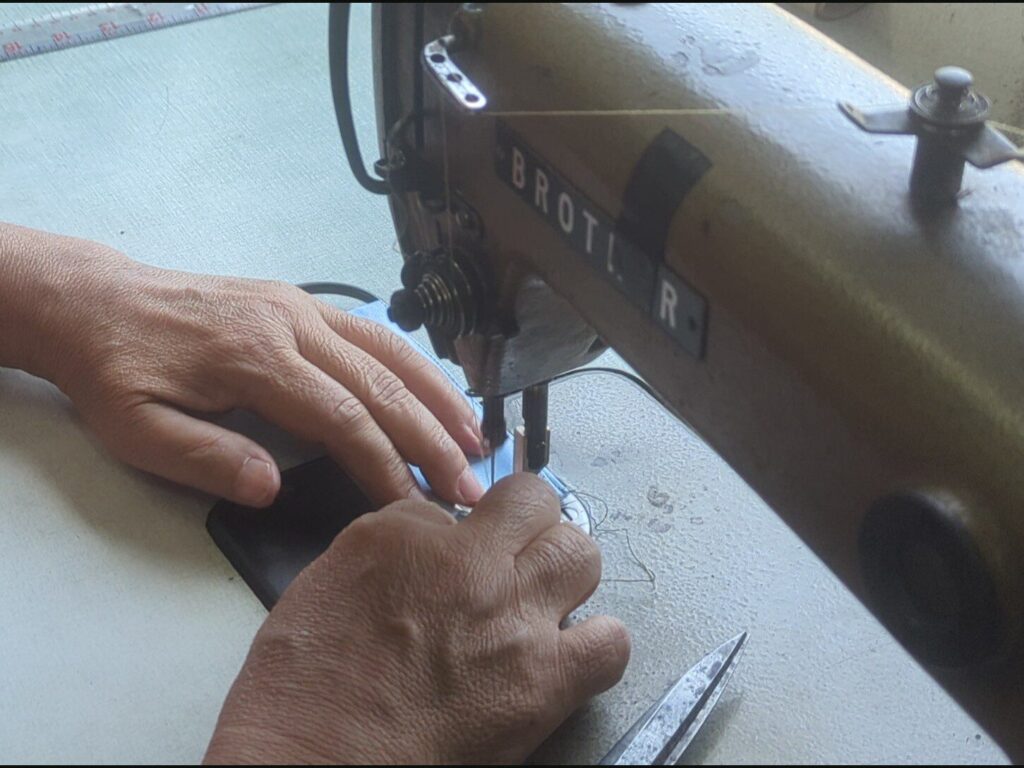 Second Chance Seamstress in Thailand handmaking a Morph Bags product from event signage.