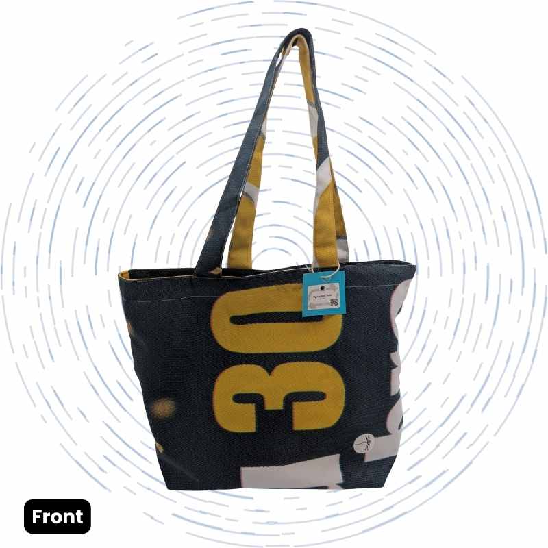 The front view of a one-of-a-kind tote bag featuring a bold yellow "30" graphic against a dark background, with dark blue, white, and yellow handles.