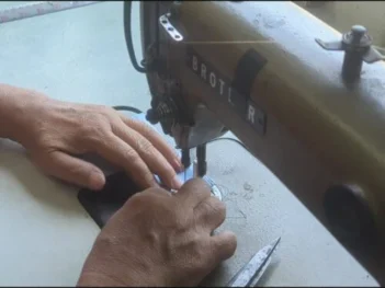 An informal seamstress in Thailand handmaking a Morph Bags product from event signage.